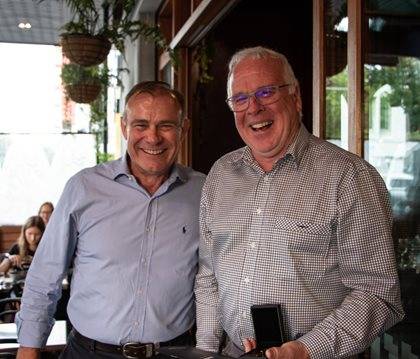 Two smiling individuals standing together inside a restaurant.