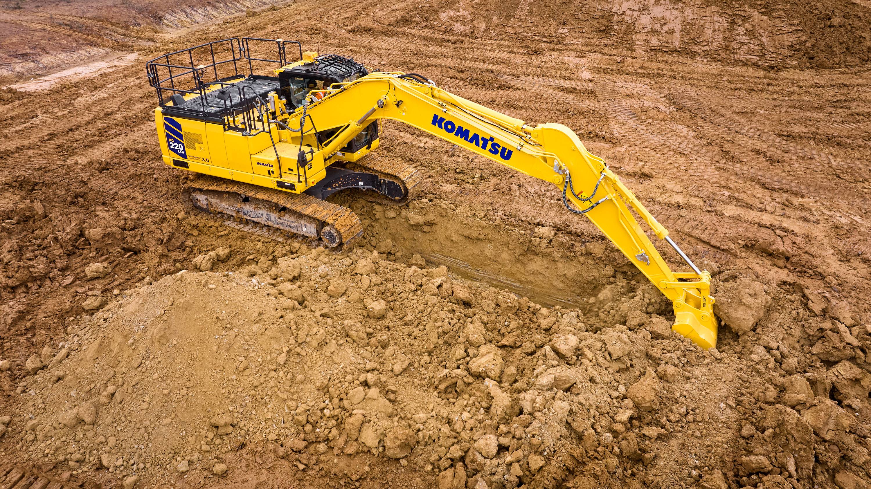 A Komatsu excavator digging into the ground on a worksite.
