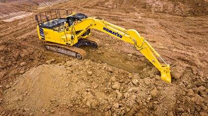 A Komatsu excavator digging into the ground on a worksite.