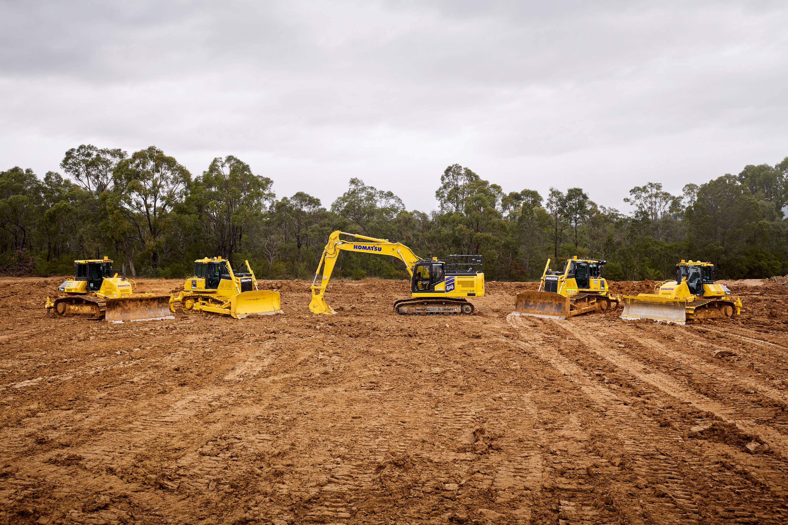 A lineup of Komatsu construction equipment, including an excavator and bulldozers.