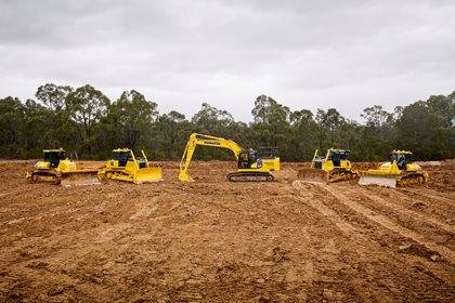 A lineup of Komatsu construction equipment, including an excavator and bulldozers.